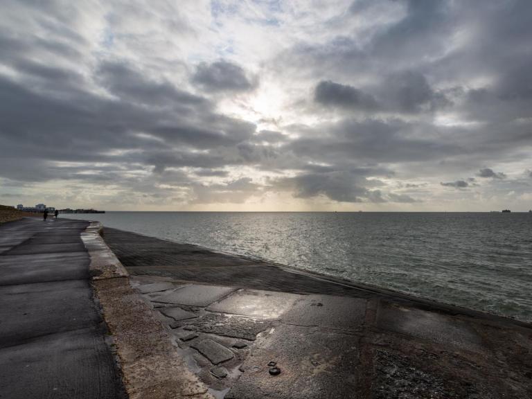 Photograph of pathway along coast, with cloudy sky over sea