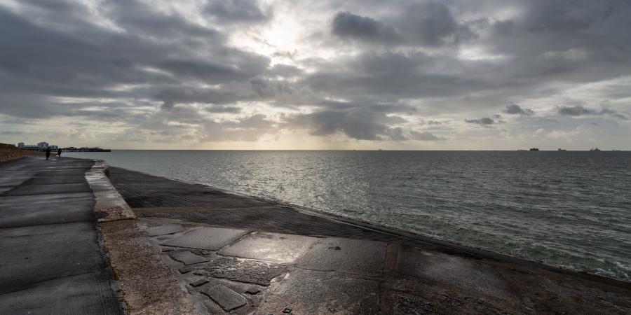 Photograph of pathway along coast, with cloudy sky over sea