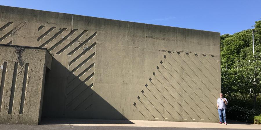 Dr Bob Clarke stands to the right of cold war concrete structure 