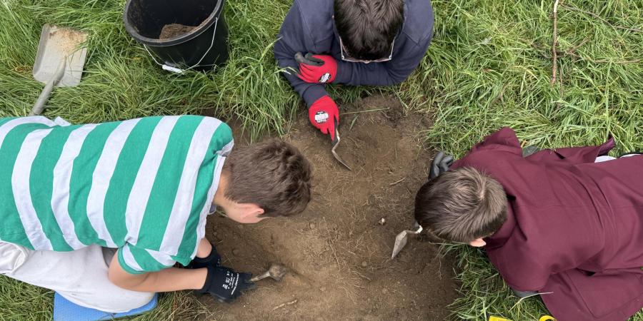 Three Year 9 students from a school in South Yorkshire excavating a trench together