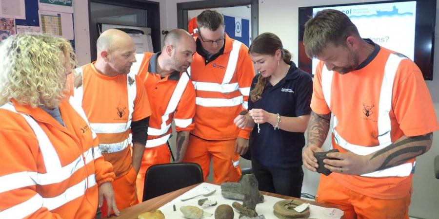 People in high vis learn about seabed archaeology from a marine archaeologist