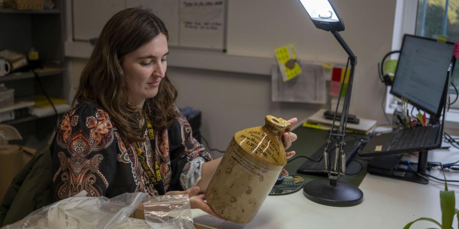 The desk is lit by bright side lamp, Jasmine inspects are very large grey and sandy yellow stoneware jug