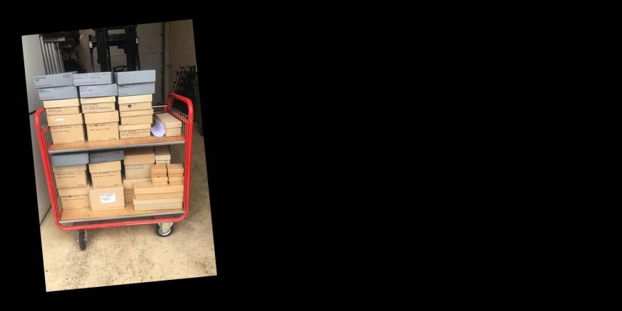 Photograph of boxes sitting on a red trolley: Oxford archives going into quarantine