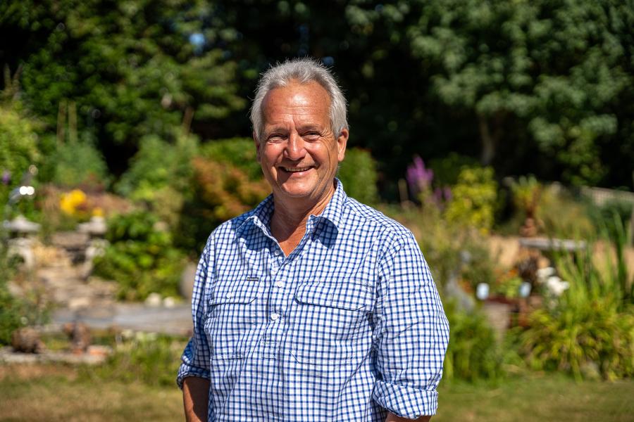 Ian Dunn, Wessex Archaeology's Chair, stands in a garden, looking at the camera and smiling