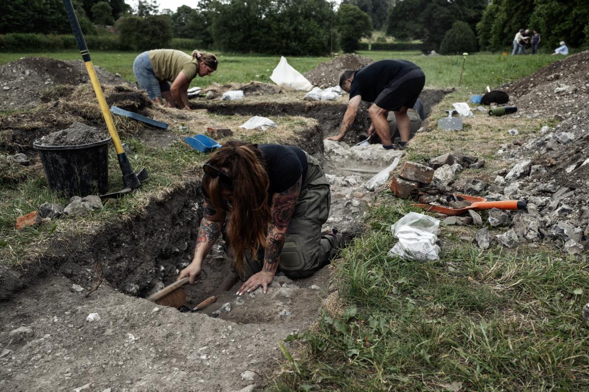Operation Nightingale volunteers excavate in a trench, mounds of spoil either side
