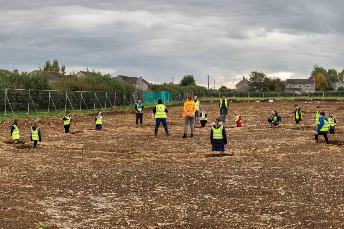 School children on site stand in the circular shape of an Iron Age roundhouse