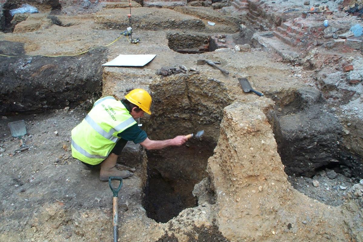 Excavating a medieval pit which cut through the lighter gravel of a Roman road at Fenchurch