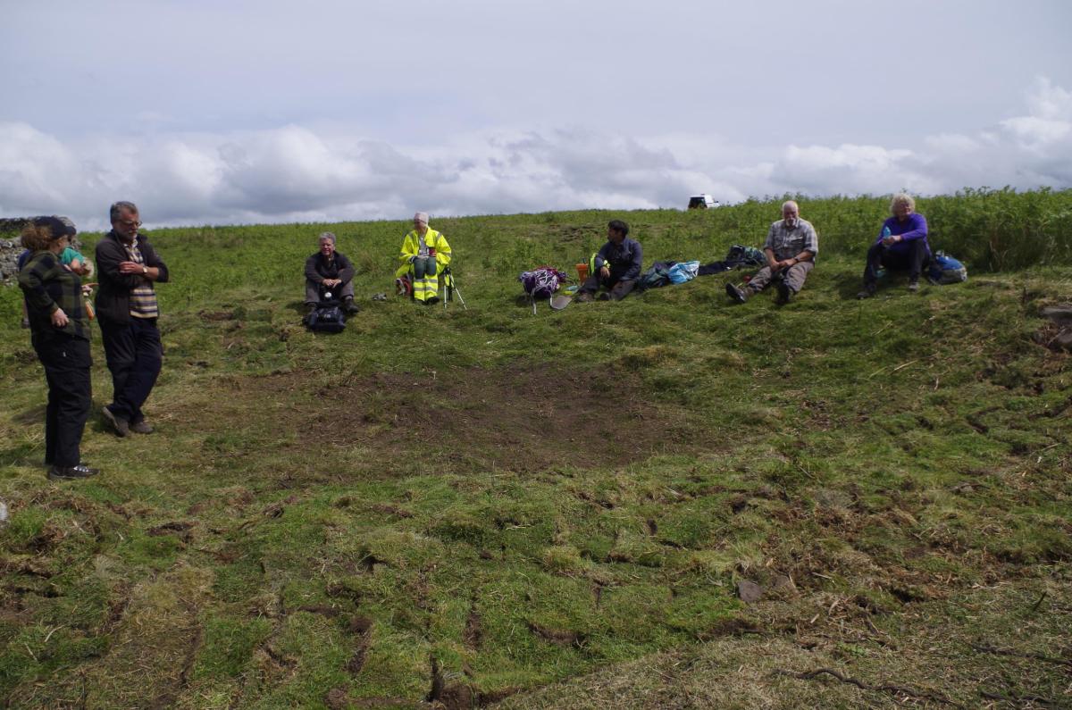 Volunteers sit near re-turfed trench at Yatesfield