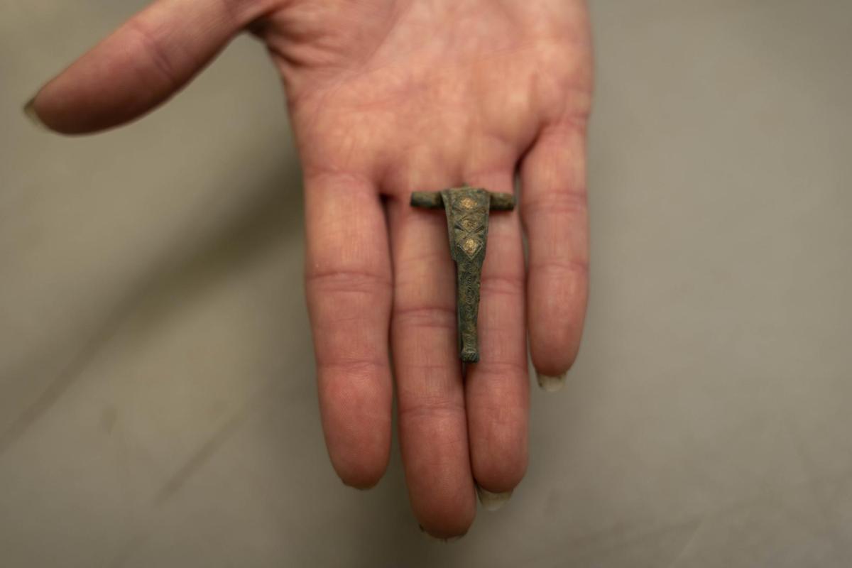 Copper T-shaped brooch in palm of a hand 