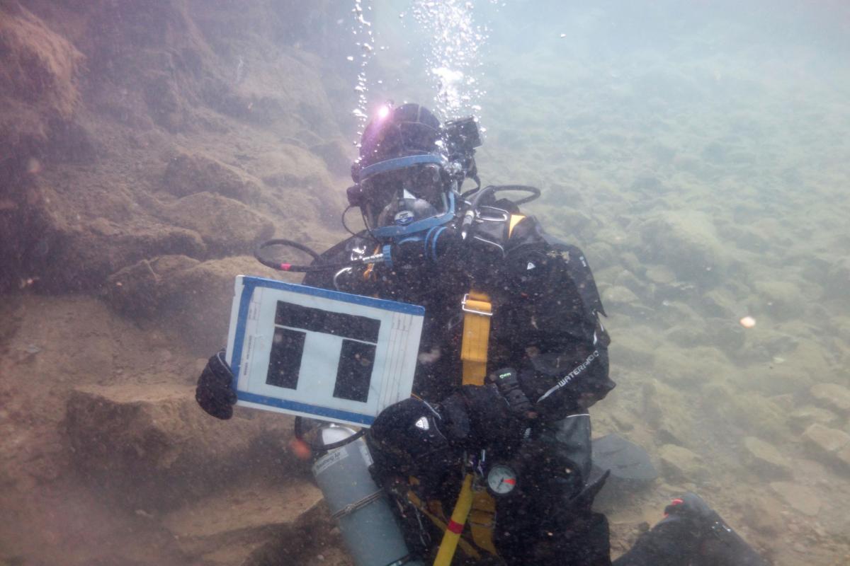 A diver holding the Wessex Archaeology logo