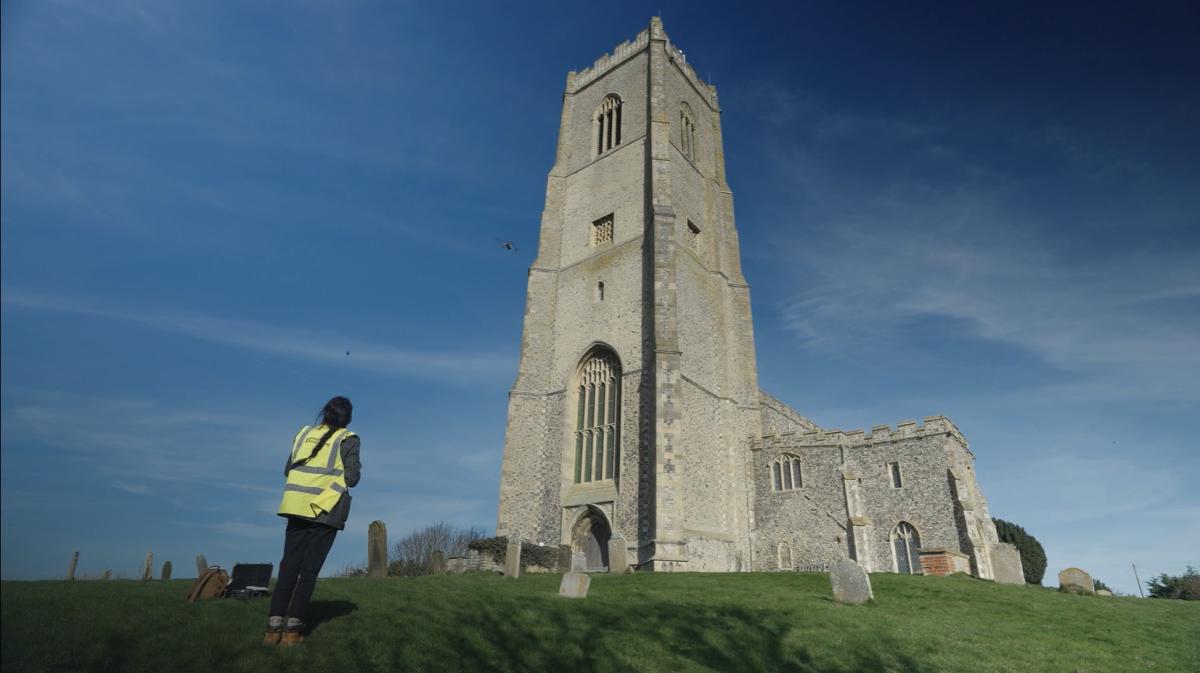 archeological survey expert undertakes drone survey of church, standing in churchyard