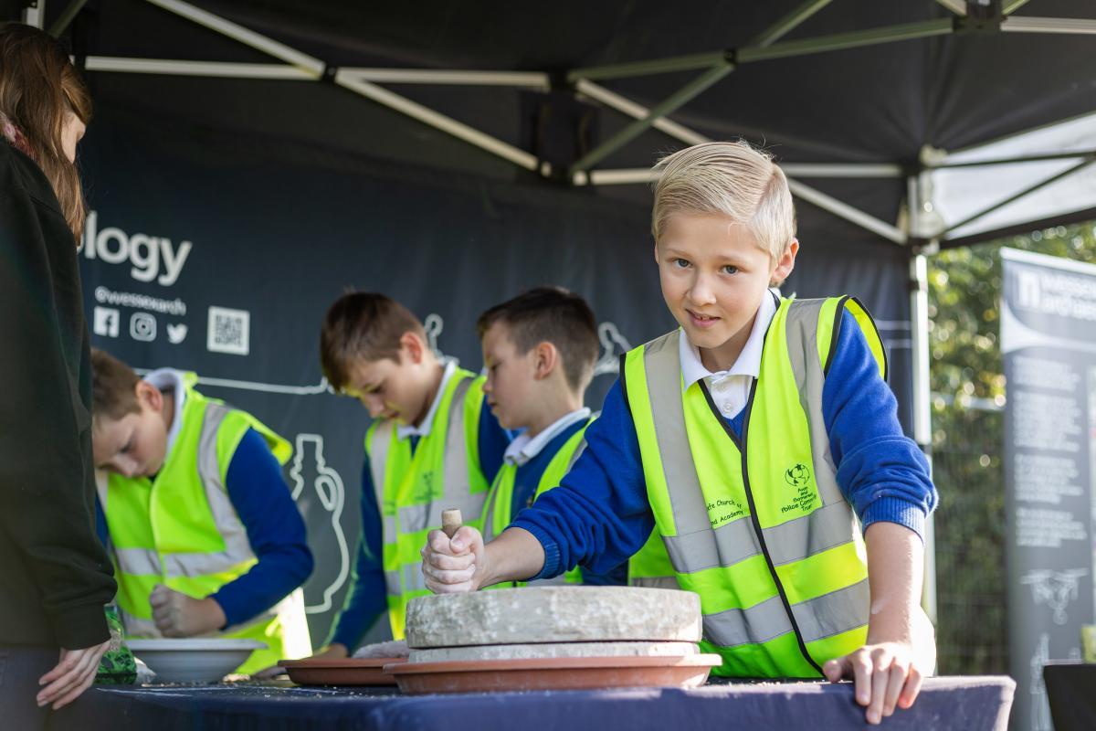 A child makes flour with a replica Roman quern stone