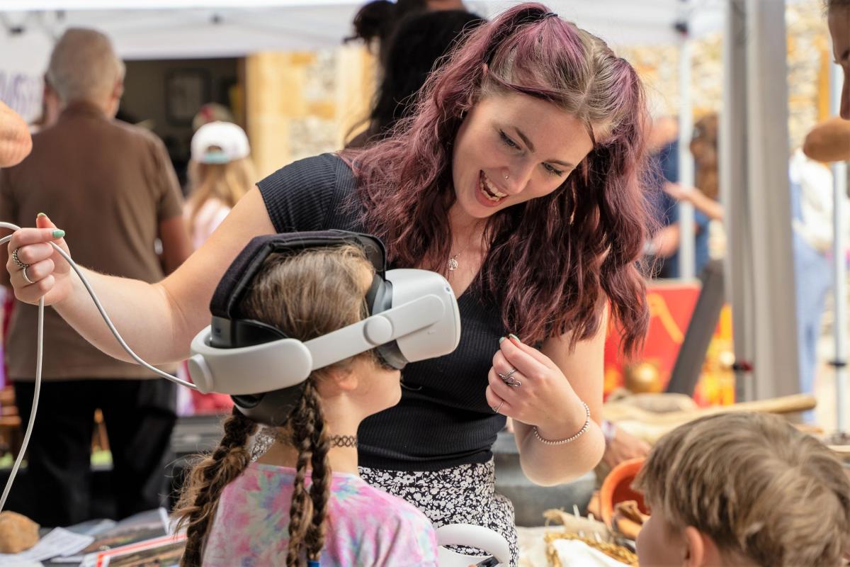 Rhiannon Piggon, Community Engagement specialist, assists a child in using a 3D Virtual Reality Experience