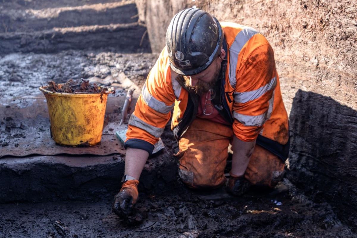 Max Dampier is shown using a small wooden tool to excavate the trackway.