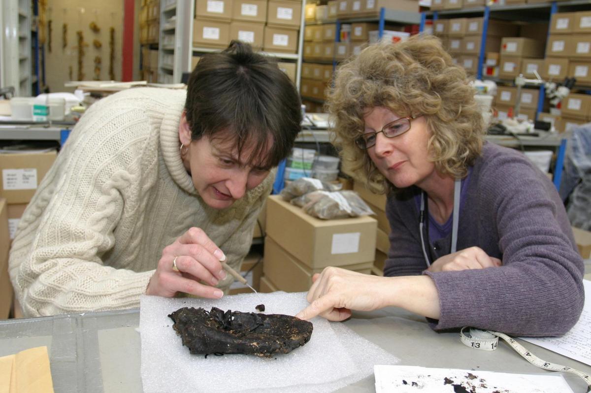 Leather specialist and an osteoarchaeologist examine a Roman child's shoes