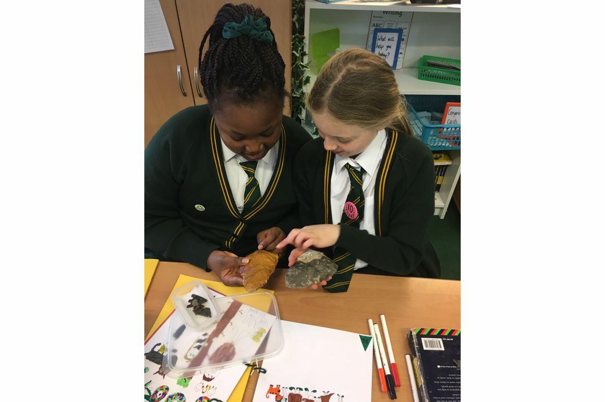 Pupils from St James' C of E Primary School studying a palaeolithic handaxe and a replica