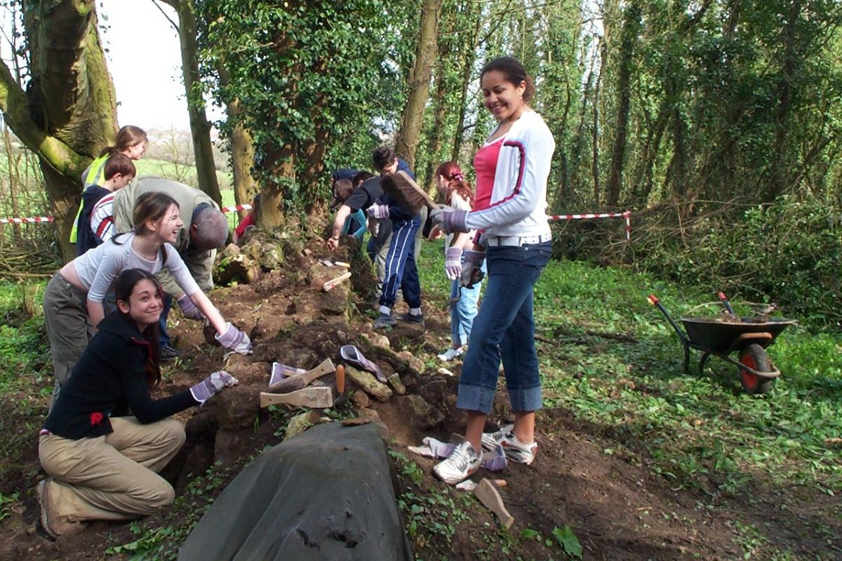 Young volunteers help to clear an old wall during the restoration work