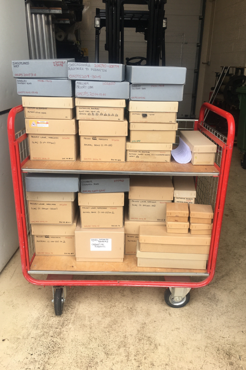 Photograph of boxes sitting on a red trolley: Oxford archives going into quarantine