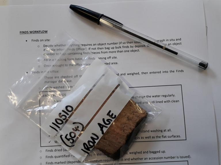 A piece of Iron Age pottery on top of a finds information sheet