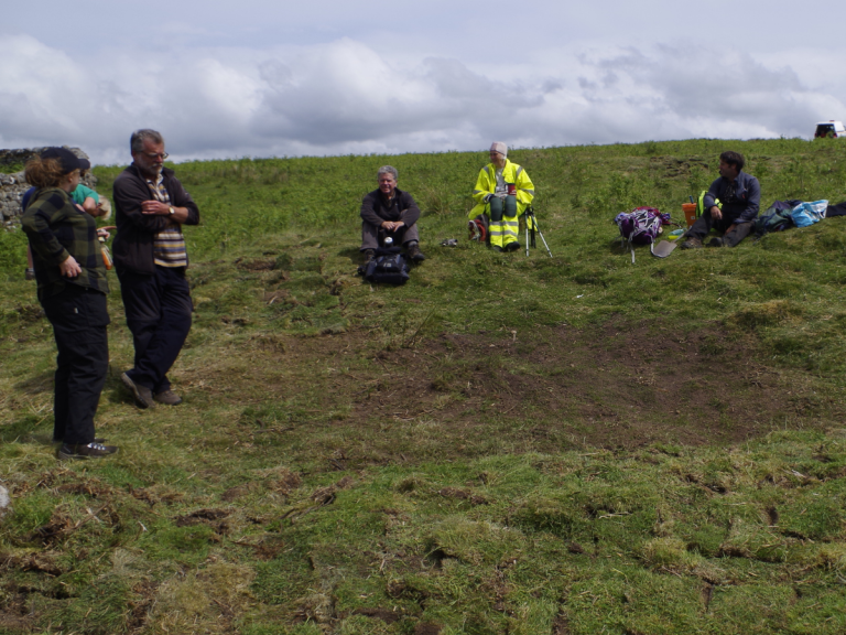 Volunteers sit near re-turfed trench at Yatesfield