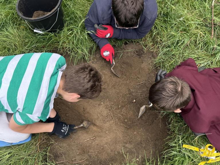 Three Year 9 students from a school in South Yorkshire excavating a trench together