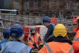 A group of archaeologists and members of the public discuss Sheffield Castle excavation